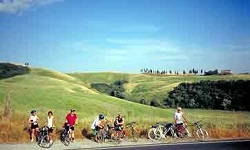 Radreisegruppe vor den sanft geschwungenen, mit Zypressen bewachsenen Hügeln der Toskana
